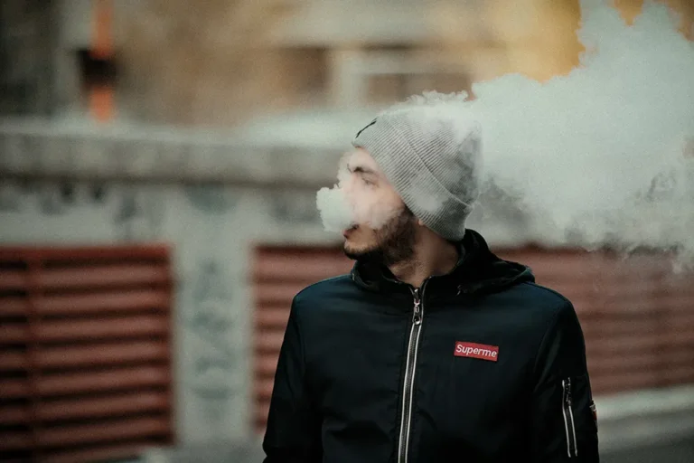 戴灰色毛帽的男子在戶外吐出電子煙蒸氣