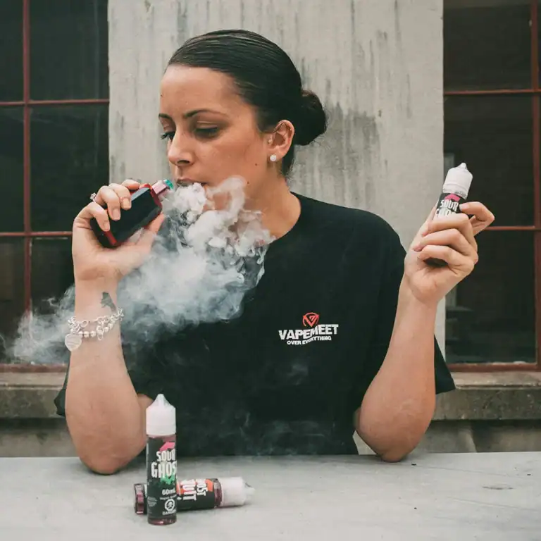 人物手持電子煙主機與煙油瓶並吐出氣霧的使用情境