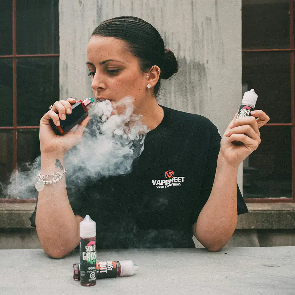 人物手持電子煙主機與煙油瓶並吐出氣霧的使用情境
